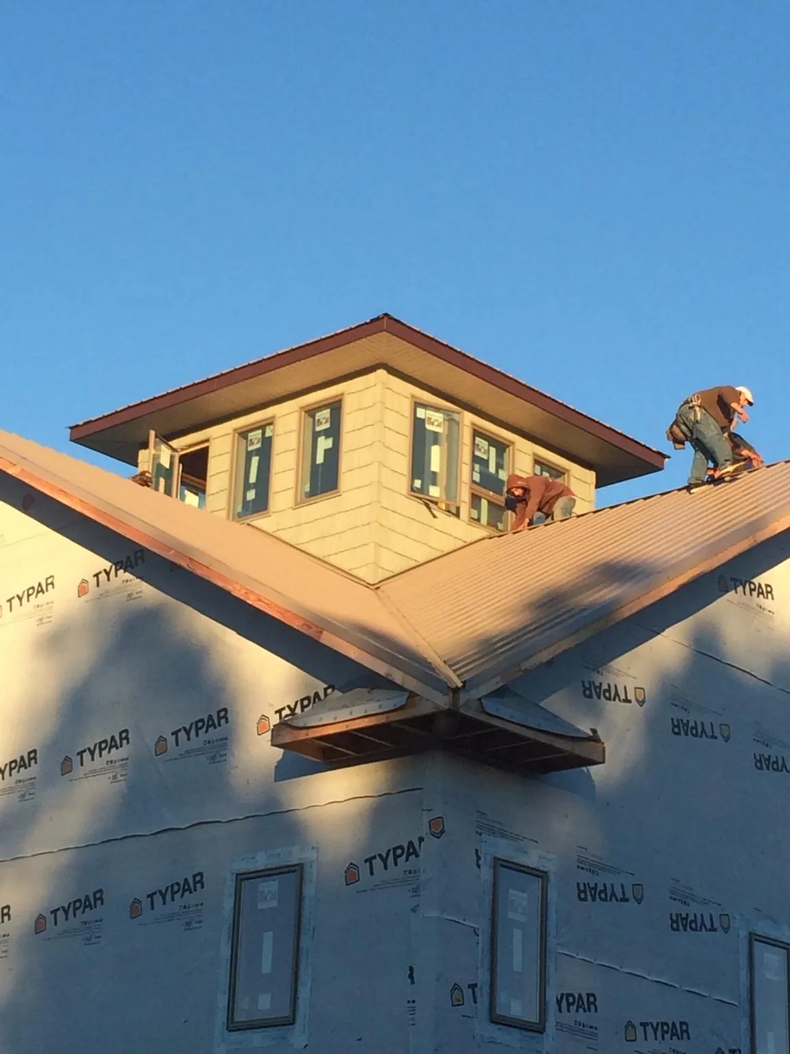 Roofers working around a rooftop cupola on a new metal roof at sunset — Roof Waterproofing in West Union by Roofing Brothers